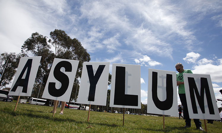A man sets up an asylum sign during a protest to support asylum seekers in front of the Parliament House in Canberra in November last year.