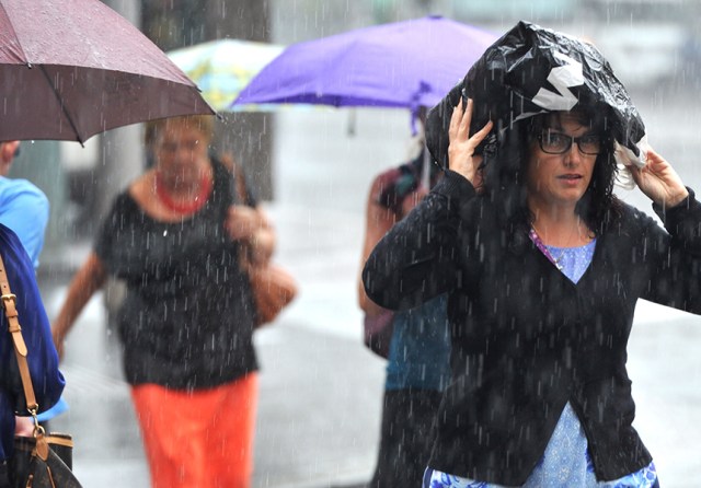 Pedestrians duck for cover as rain slams Sydney.