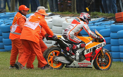 Marc Marquez is helped back on to the track after crashing out. Photo: Getty