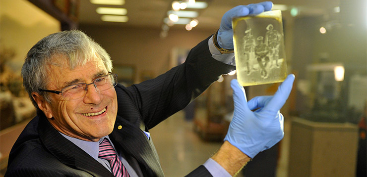 Stokes with holding up a glass negative from WW1 at the Australian War Memorial in Canberra, Thursday, Aug. 9, 2012. It was one of 800 artefacts he donated. Photo: AAP