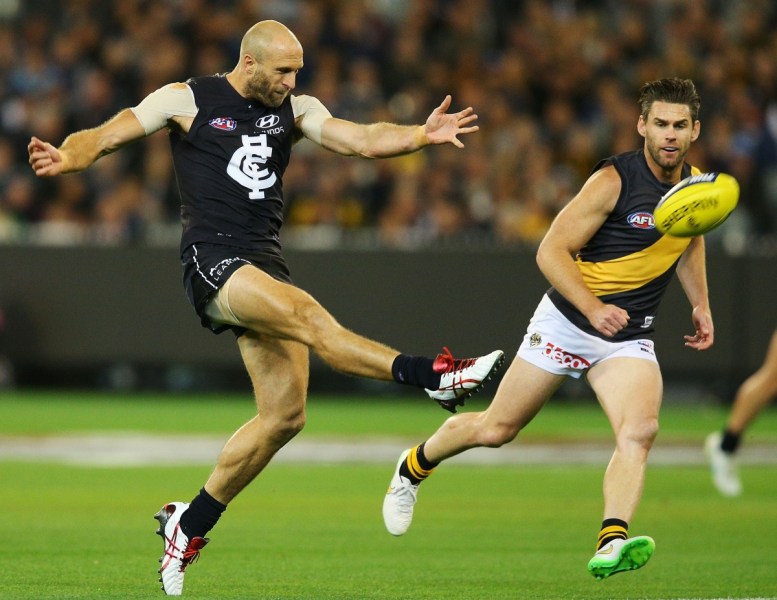 Chris Judd of the Blues kicks the ball past Chris Newman of the Tigers. Photo: Getty