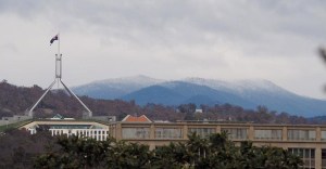 Snow capped mountains in Canberra, with Parliament House in the foreground.
