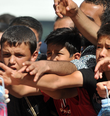 Red Cross hand out water to refugee children.