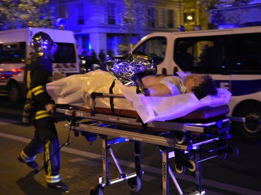 A rescuer evacuates an injured person on Boulevard des Filles du Calvaire, close to the Bataclan concert hall. AFP PHOTO / MIGUEL MEDINA