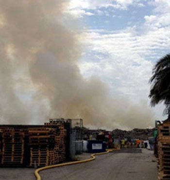 Wooden pallets near the pile of burning rubbish and building supplies. 