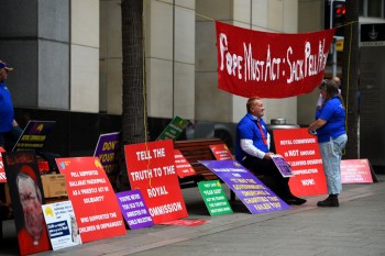 Demonstrators are seen with placards outside the commission in Sydney. Photo: AAP