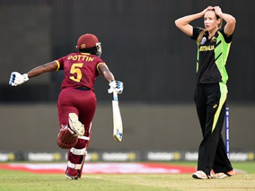 West Indies's Deandra Dottin celebrates after scoring the winning runs as Australia's Ellyse Perry reacts during the World T20 cricket tournament women's final match between Australia and West Indies at The Eden Gardens Cricket Stadium in Kolkata on April 3, 2016. / AFP / INDRANIL MUKHERJEE (Photo credit should read INDRANIL MUKHERJEE/AFP/Getty Images)