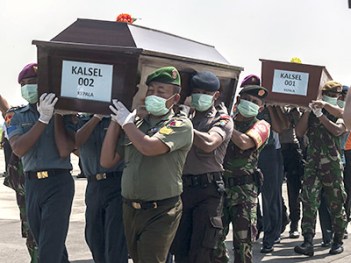 Indonesian police and military personnel carry coffins with the remains of a passengers of the AirAsia flight 8501 in Surabaya, eastern Java island, on January 17, 2015. Indonesian divers again failed to reach the main body of an AirAsia plane that crashed into the sea last month with 162 people on board, as strong underwater currents hampered efforts. AFP PHOTO / Juni KRISWANTO (Photo credit should read JUNI KRISWANTO/AFP/Getty Images)