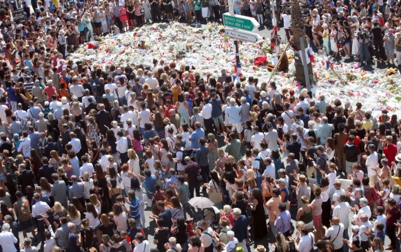 People gather at a makeshift memorial to observe a minute of silence to honour the victims of an attack in Nice.