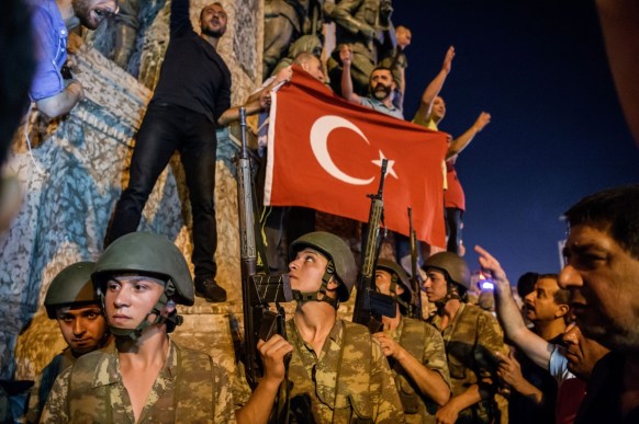 Turkish solders stand with weapons as people protest against the military coup in Istanbul.