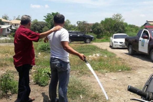 A police officer (in red) stands with the neighbour who hacked off Cola's legs as they re-enact the incident.