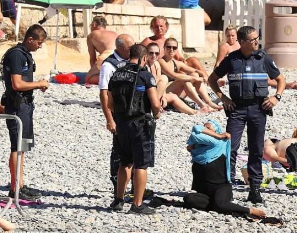 Armed police in Nice ask a woman to remove her burkini. Photo: Twitter.