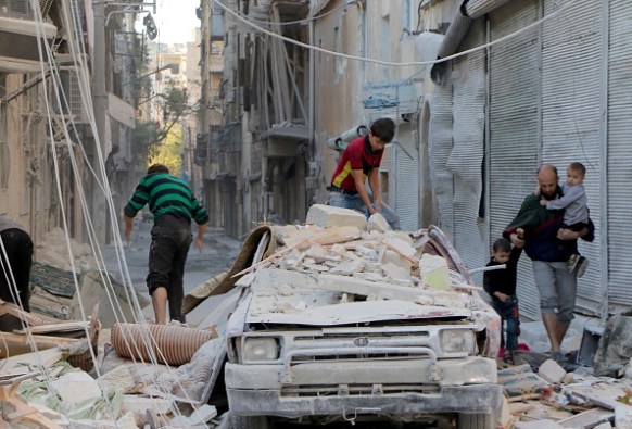 Syrians inspect the debris of collapsed buildings. Photo: Getty
