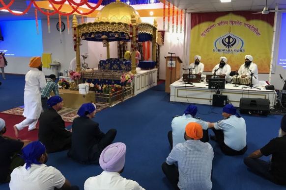 People gather at Manmeet Alisher's memorial at the Sikh Temple at Eight Mile Plains.