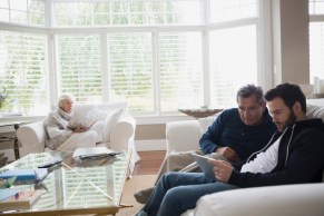 Father and son using digital tablet living room sofa