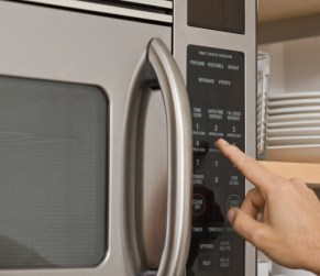 Man pushing button on microwave