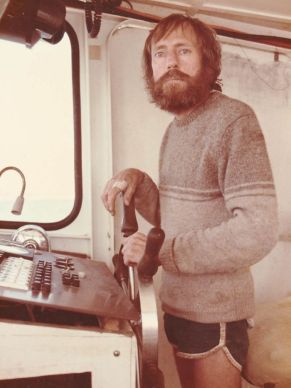 Col Meyers at the wheel of a fishing boat, looking in dire need of a good sleep.