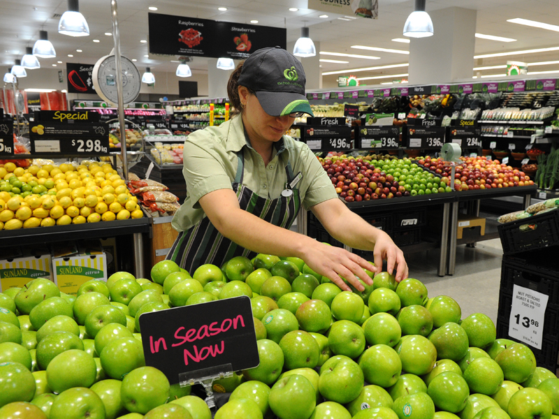 An employee arranges fruit inside a Woolworths grocery store