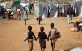 Three children walk through a UN camp