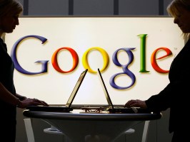 People working on laptops in front of the Google logo
