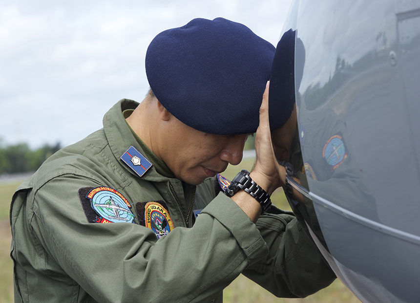 An Indonesian Navy airman prays next to his plane before a search flight.