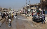Iraqi bystanders gather at the site of a car bomb in the Al-Amil district.
