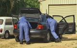 Police forensics officers search a vehicle at a house in Townsville.