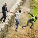 A police officer sprays tear gas onto migrants trying to access the Channel Tunnel in Calais.