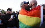 A couple shares a kiss as they embrace each other under a pride flag in the US.