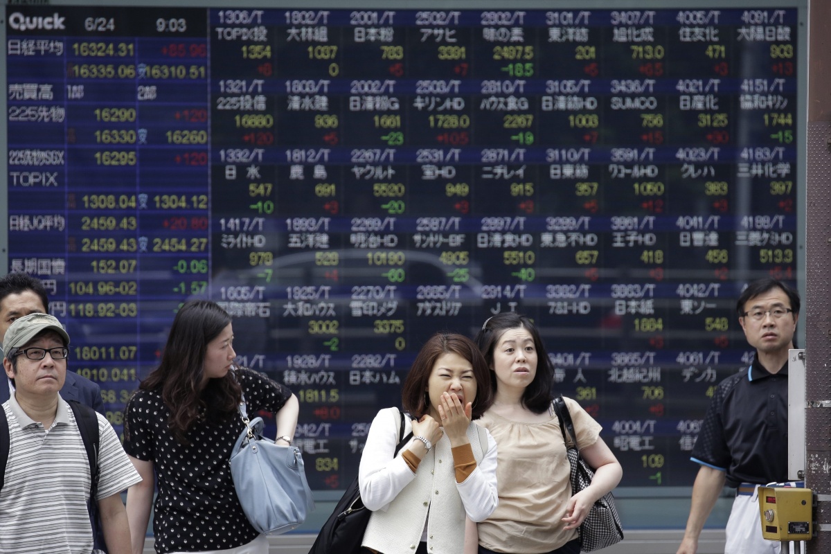 Pedestrians at a monitor displaying the Tokyo stock index.
