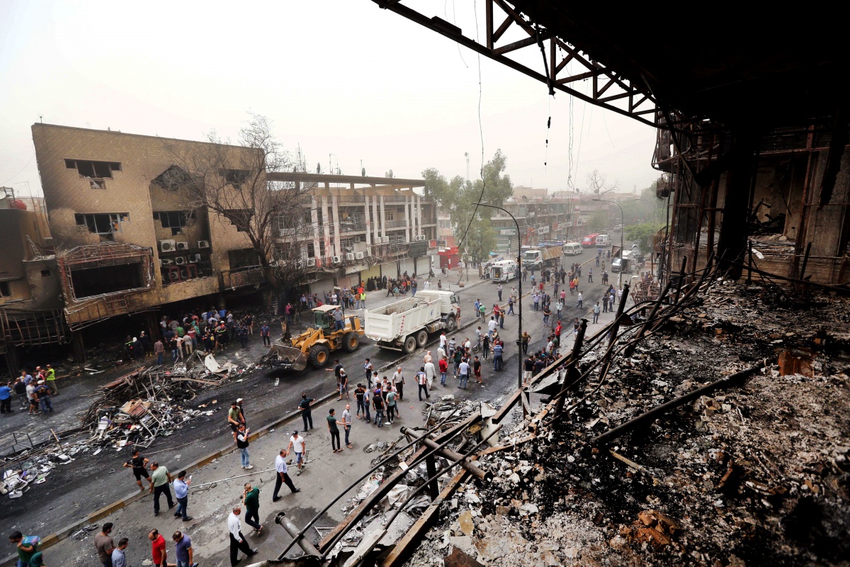 Iraqi security forces and civilians gather at the site after a car bomb hit Karrada.