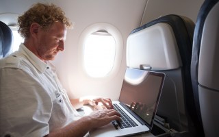 man using laptop on plane