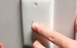 A hand turns on a light switch