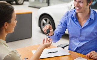 Young woman handing car key to a man