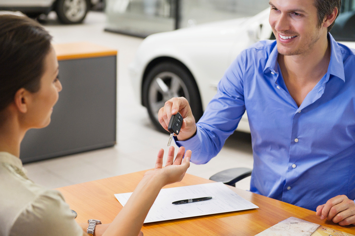Young woman handing car key to a man