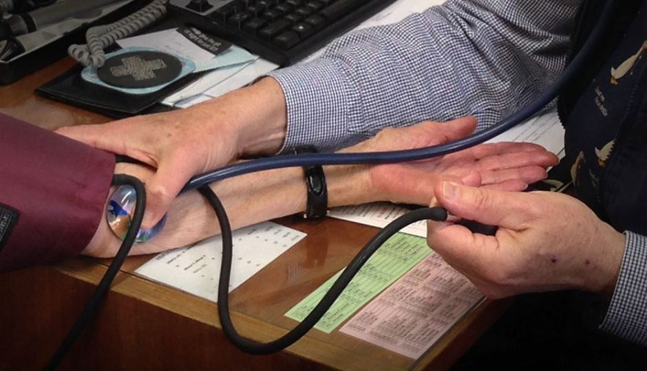 Close up of doctor taking patient's pulse using stethoscope