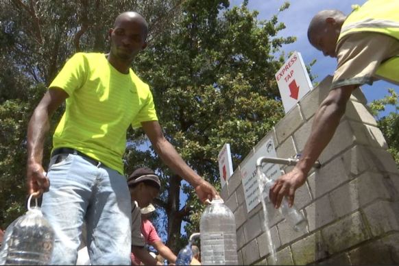 Cape Town residents pour water from a public tap