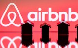 Small figurines of houses sit infant of a red screen.