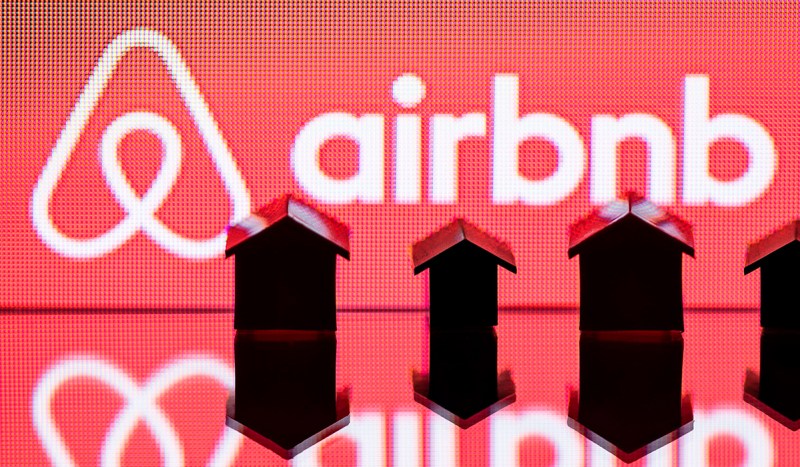 Small figurines of houses sit infant of a red screen.