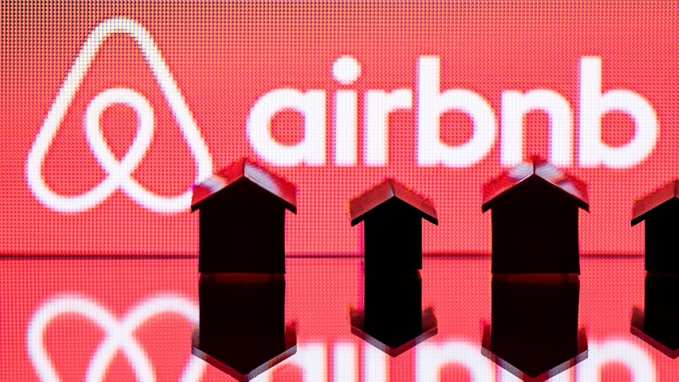 Small figurines of houses sit infant of a red screen.