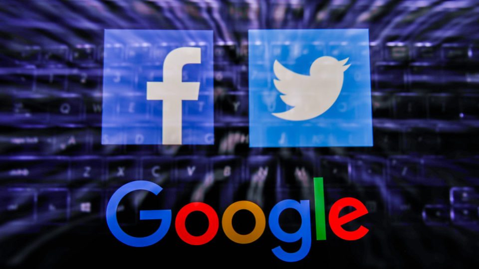 social edia Facebook, Twitter and Google logos displayed on a phone screen and keyboard