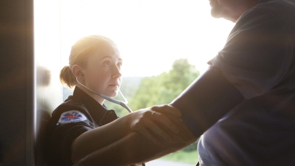 Paramedic checks patient's blood pressure.