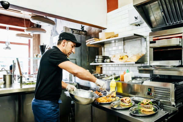 A chef working at a trendy burger bar preparing food for his customers.