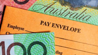 Pay envelope surrounded by hundred dollar notes.
