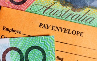 Pay envelope surrounded by hundred dollar notes.