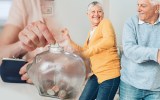 Older couple celebrating while putting money in a jar.