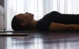 A person trying to relax while listening to guided meditation on her smartphone at home.