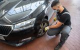 A mechanic in a mask changes a car tyre