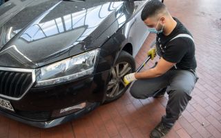 A mechanic in a mask changes a car tyre