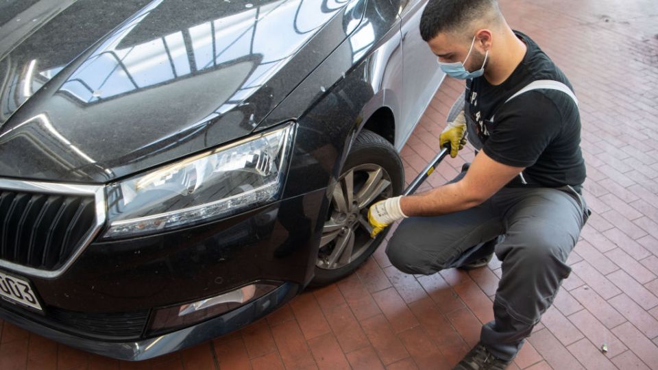 A mechanic in a mask changes a car tyre